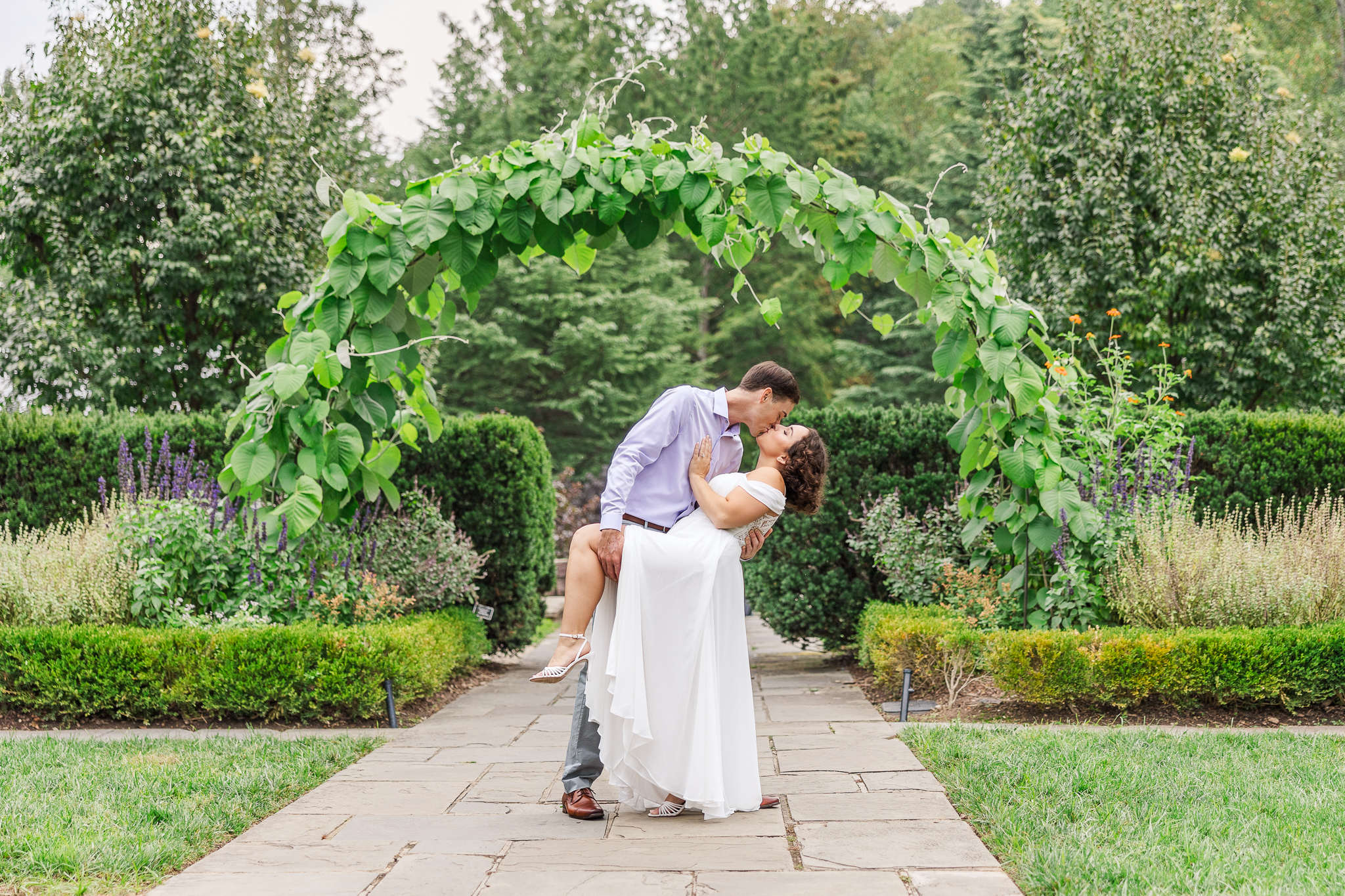 couple kissing under greenery arch at Brookside Gardens