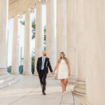 A man and woman hold hands as they walk inside of the Jefferson Memorial