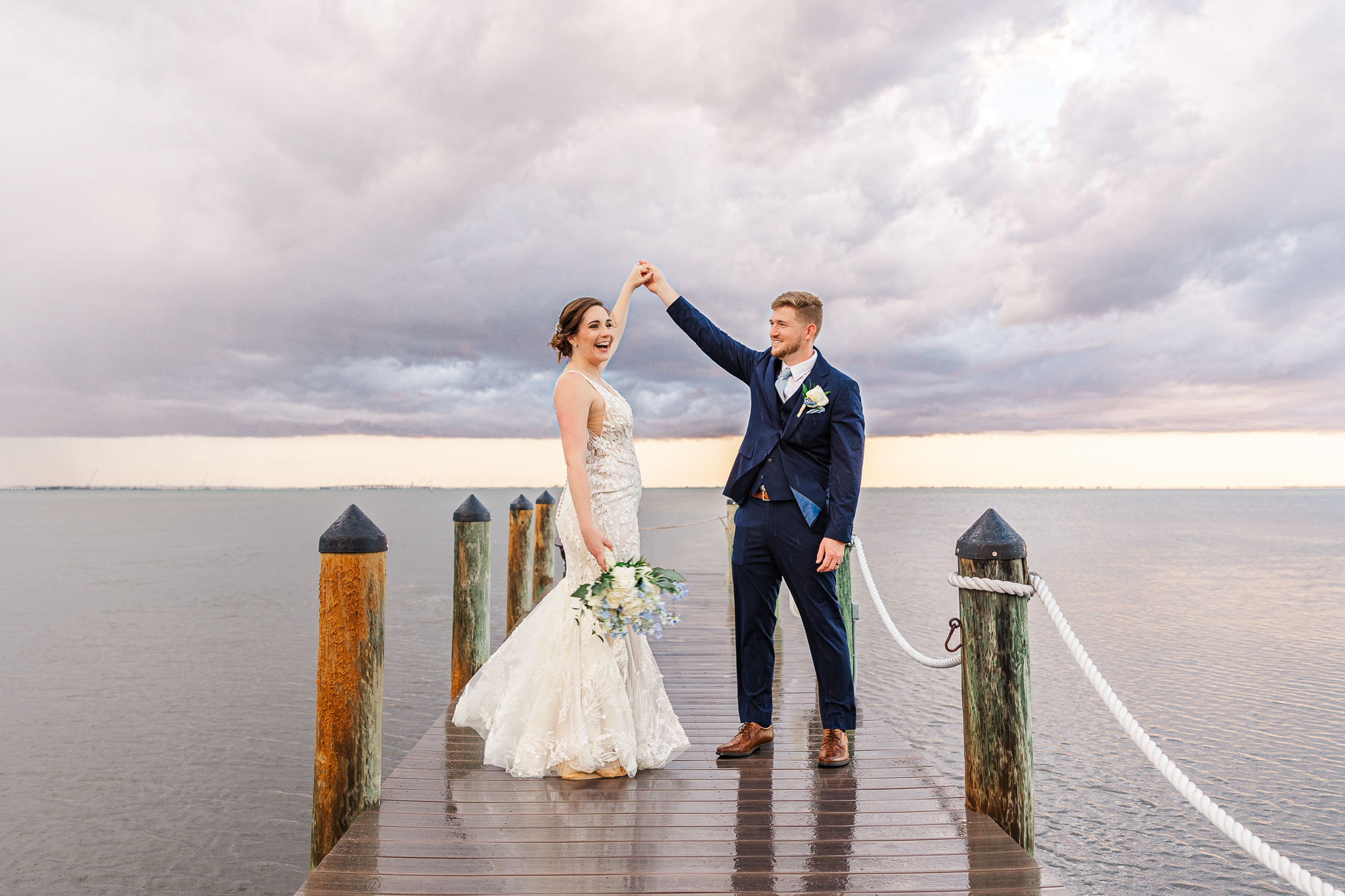 A bride and groom dance at the end of a boat dock