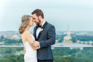 A bride and groom embrace with the Washington Monument in the background