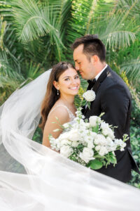 A bride and groom embracing with the veil flowing towards the camera